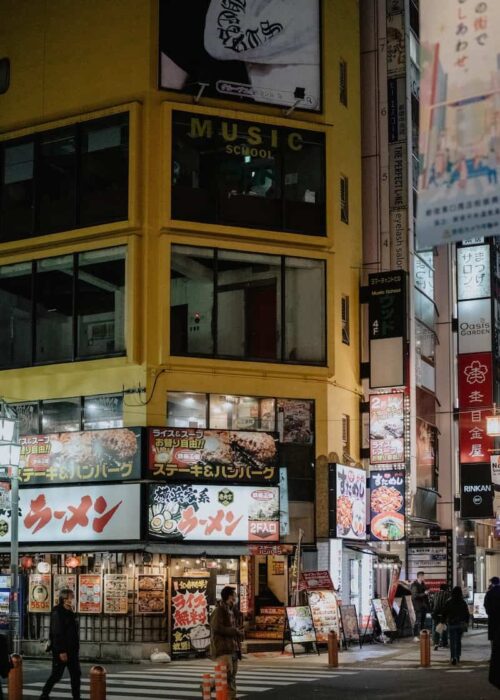 a busy city street at night with people crossing the street